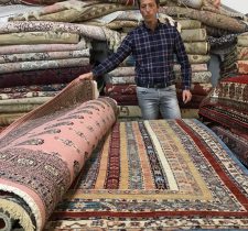 Homme présentant des tapis orientaux.
