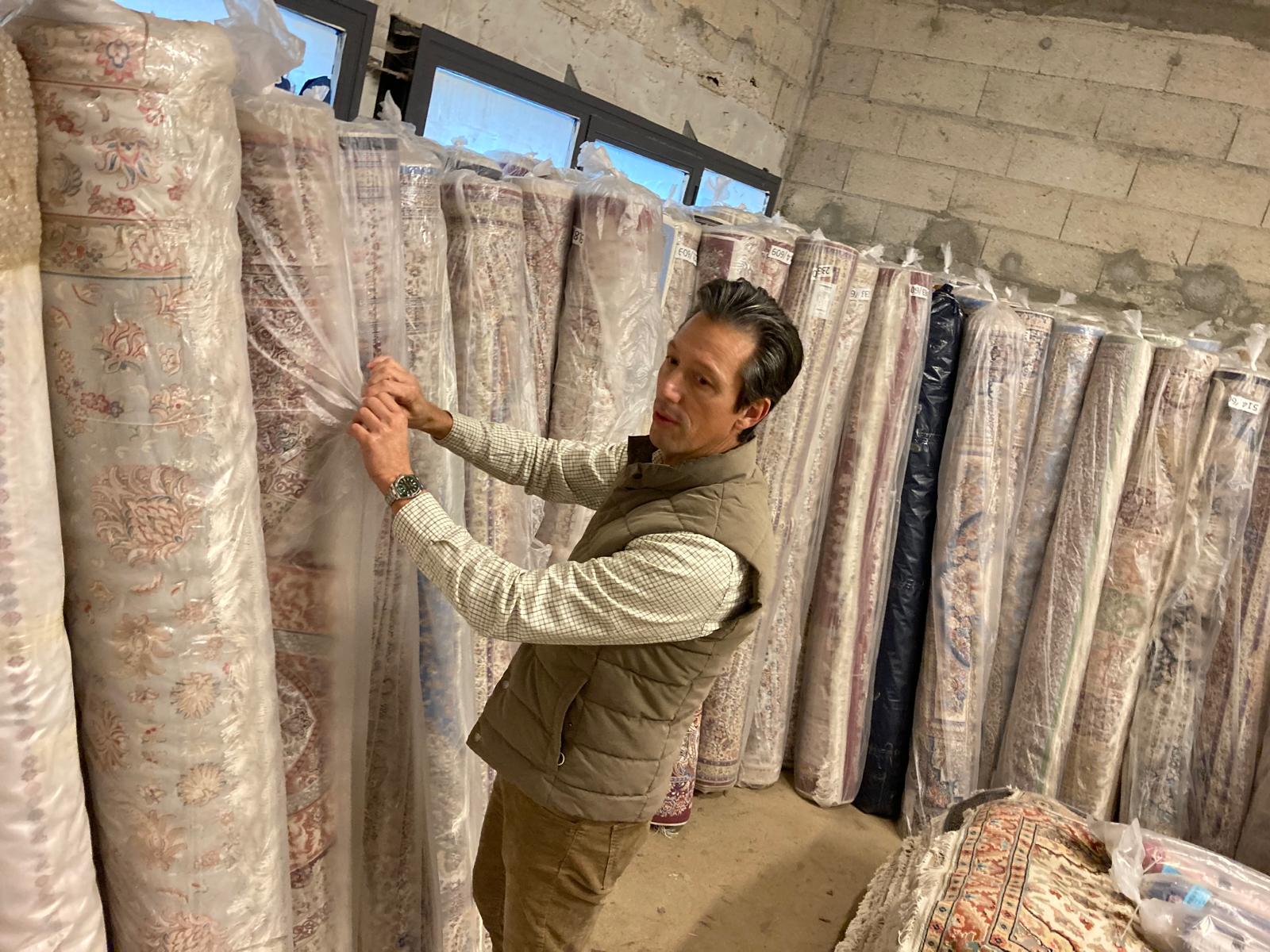 Homme examinant des tapis orientaux.