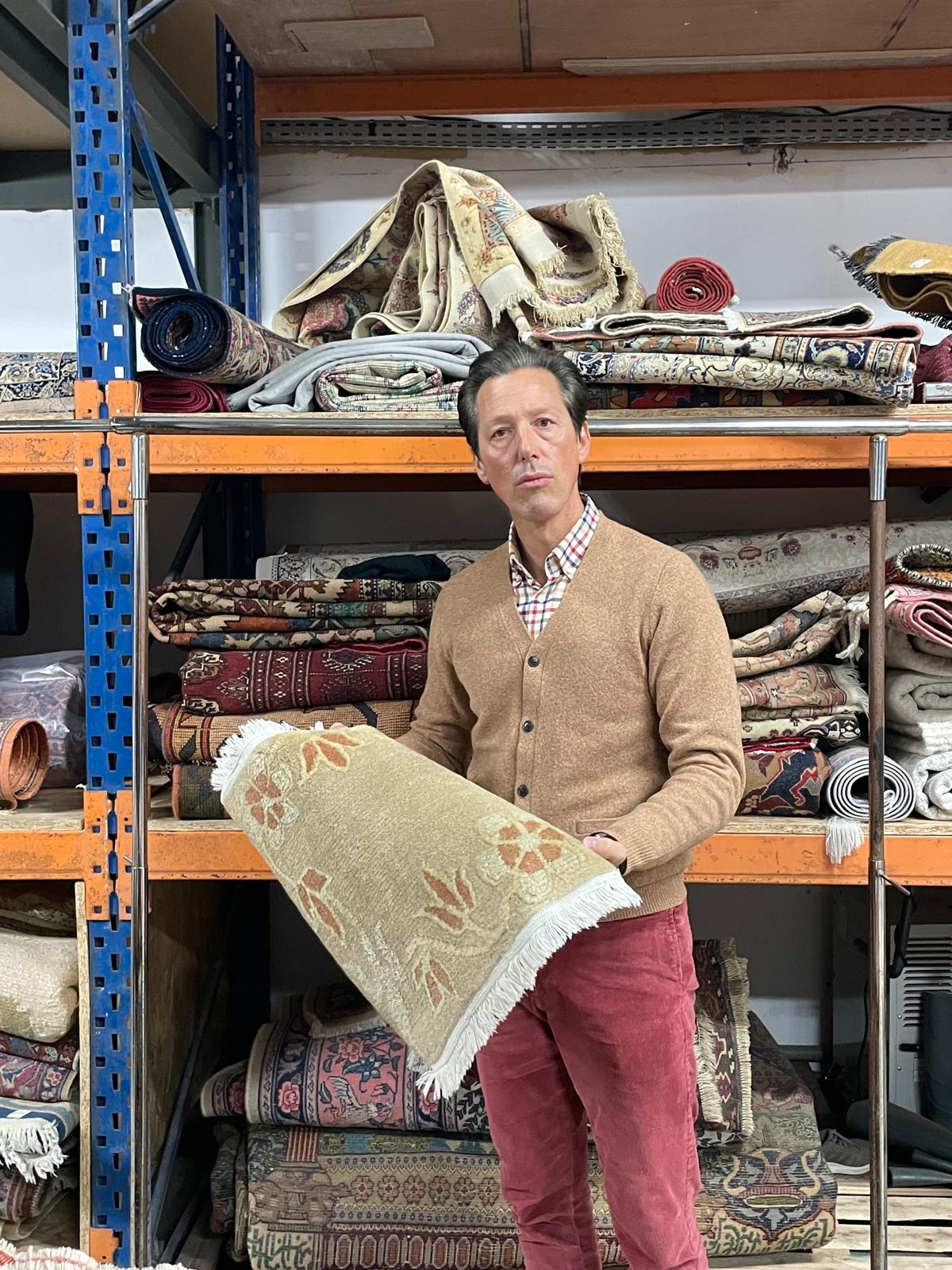 Homme tenant un tapis oriental.