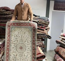 Homme tenant un tapis oriental.