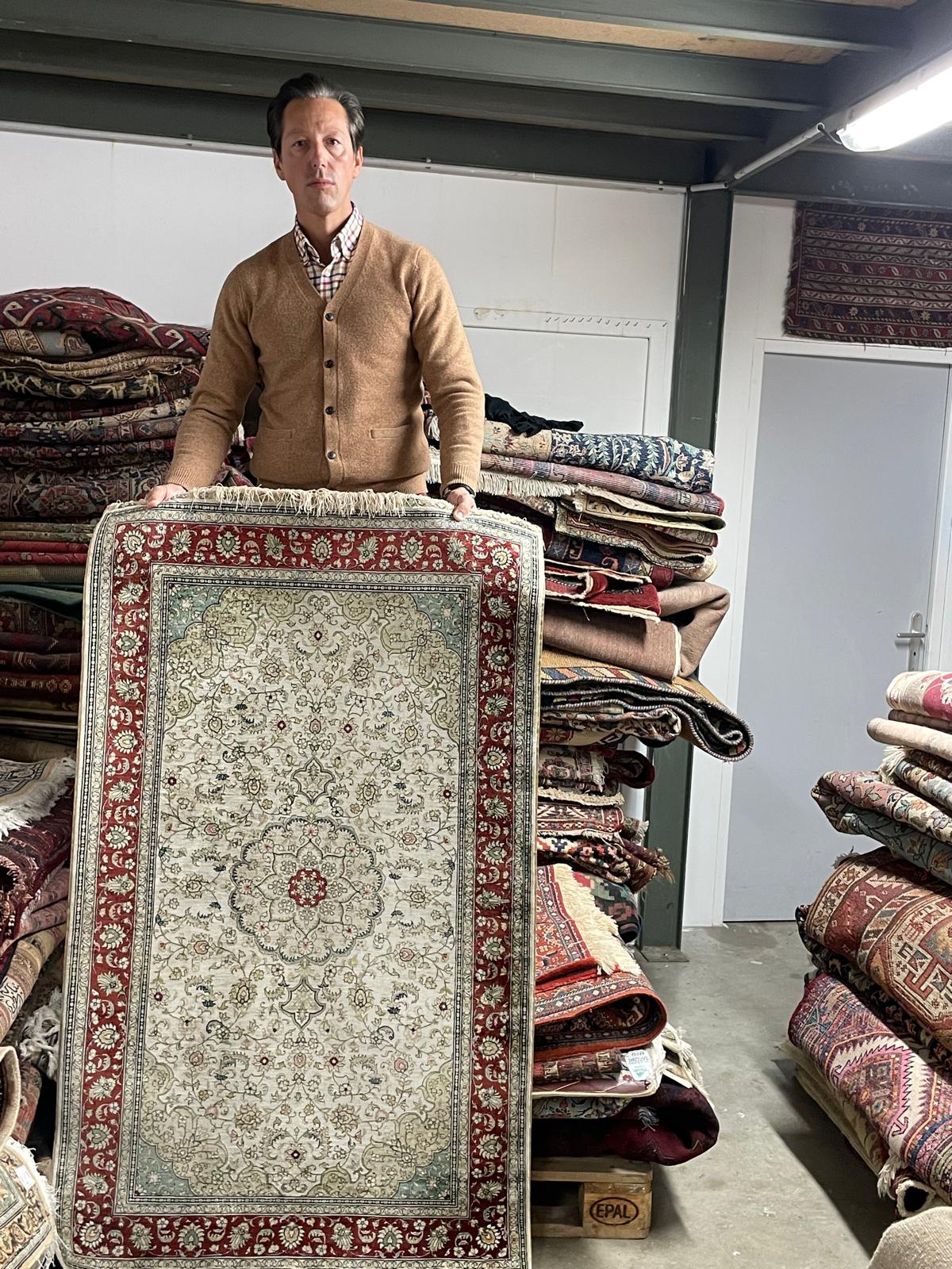 Homme tenant un tapis oriental.