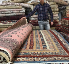 Homme présentant des tapis colorés.